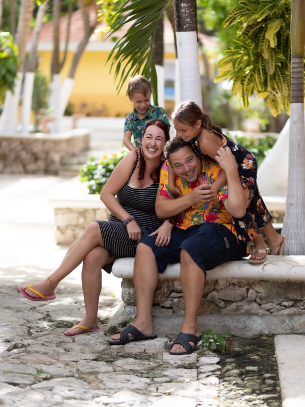 Famille assise sur un muret de pierre sous des palmiers à Playa del Carmen