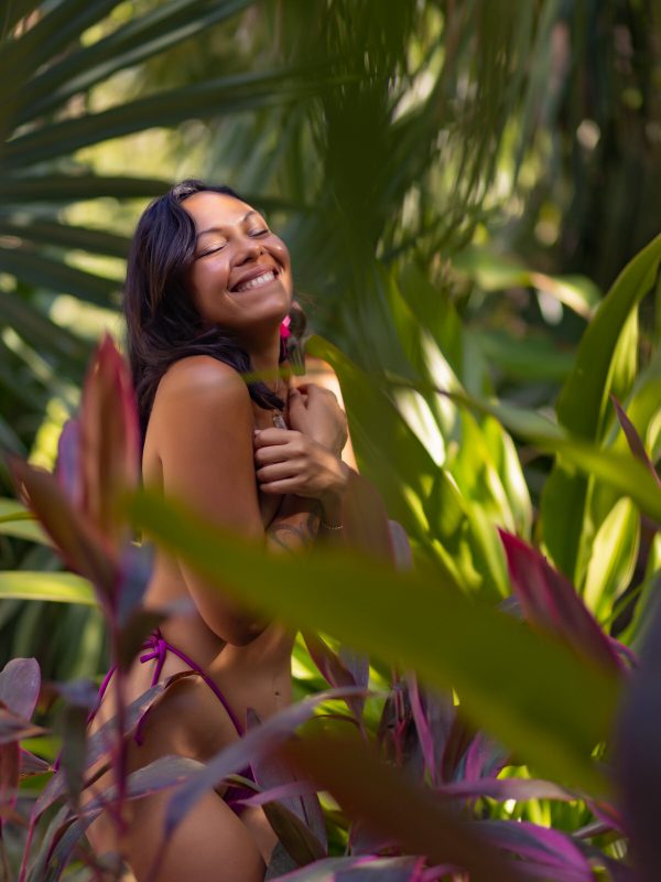 Femme riant parmi des plantes tropicales colorées à Playa del Carmen